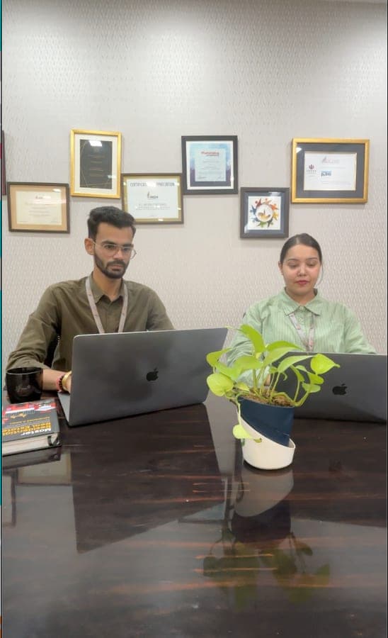 Two DC Jain team members working at their desks